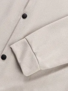 Détail en gros plan de la texture en maille gaufrée beige sur une manche de veste de travail