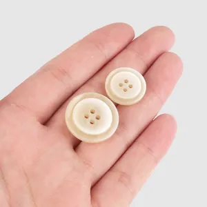 High-end beige resin buttons for coats and shirts, two sizes shown in hand for scale.
