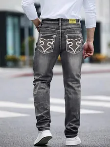 Detail view of men's dark grey denim jeans featuring unique embroidered back pockets.