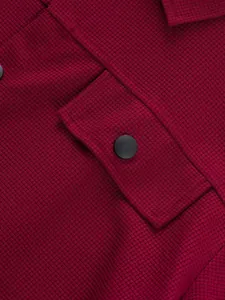 Détail de la texture gaufrée rouge vin d'une veste de travail avec bouton pression noir