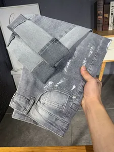 Primo piano di jeans lavati grigi con schizzi di vernice bianca e finitura vintage invecchiata