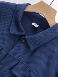 Détail de la veste de travail en maille gaufrée bleue avec col boutonné et étiquette