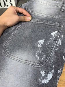 Dettaglio della tasca posteriore e schizzi di vernice bianca su jeans grigi lavati