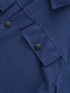 Détail de la texture gaufrée bleue sur une veste avec rabat de poche à bouton pression