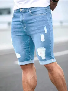 Detail of light blue distressed denim shorts with ripped design and rolled cuffs