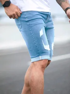 Detailed view of men's summer ripped denim shorts featuring bleached wash and frayed edges