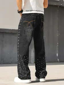 Detail of men's black straight-leg jeans with sparkling rhinestone embellishments