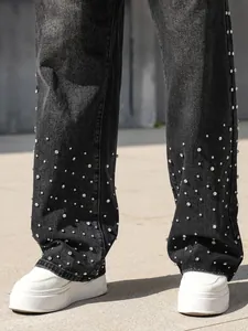 Detail view of men's loose straight black denim pants with rhinestone embellishments