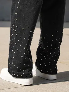 Detailed macro view of black denim jeans featuring premium sparkling rhinestone embellishments