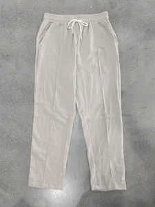 Top view of beige men's loose linen casual pants with white drawstring on concrete floor