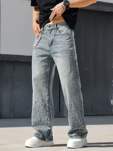 Close-up of men's straight jeans showing intricate rhinestone decorations on light blue denim.