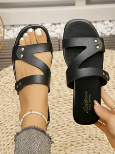 Detailed close-up of retro black flat sandals featuring gold rivets and stylish Z-strap