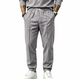 Detail view of men's grey cotton linen pants with drawstring waist and seams.