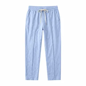Detailed view of light blue cotton linen straight-leg trousers with drawstring waist.