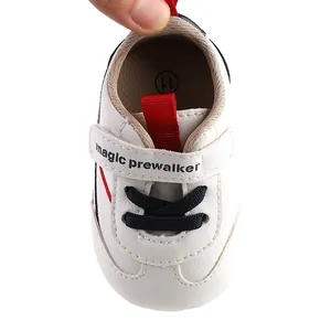 Top-down detail view of white baby pre-walker shoe with velcro strap and navy laces