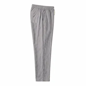 Side view detail of gray cotton linen trousers with elastic waist and side pocket.