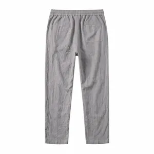 Back view of grey cotton linen trousers featuring elastic waist and rear pocket design.
