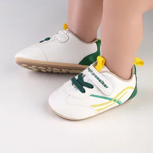 Detailed close-up of white baby prewalker shoes with green and yellow accents and velcro