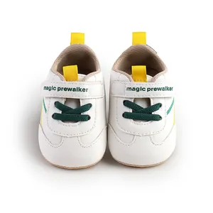 Detail view of white soft sole baby prewalker shoes with green laces and yellow straps.