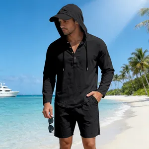 Detail shot of a black hooded Henley shirt and linen shorts on a tropical beach.