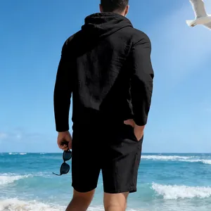 Back view of a man wearing a breathable black linen hoodie and shorts set on a sunny beach