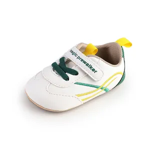 Close-up view of white baby prewalker sneakers with green laces and magic strap.