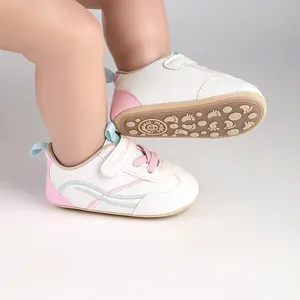 Detail of white infant walking shoes with pink accents and anti-slip footprint sole