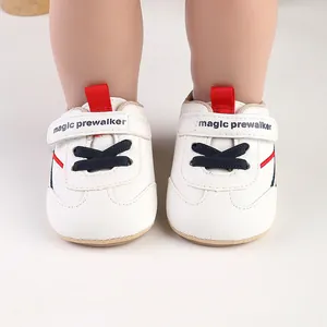 Close-up of white baby pre-walker shoes with magic prewalker text and red pull tabs.