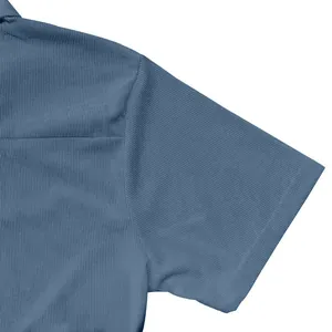 Détail d'un polo en velours côtelé bleu montrant la texture fine du tissu et les coutures.