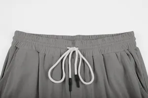 Close-up of grey corduroy pants waistband with white drawstring and ribbed texture.