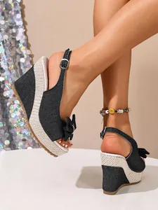 Detailaufnahme schwarzer Denim Keilsandaletten mit Schleife und Plateausohle aus Stroh