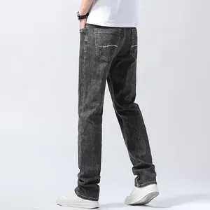 Detail view of men's loose straight-leg jeans in washed grey with pocket stitching.