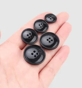 Close-up view of premium black resin four-hole buttons in various sizes held in hand