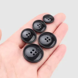 High-quality black resin 4-hole buttons for coats and jackets presented in hand