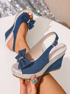 Nahaufnahme blauer Denim-Keilsandalen mit stilvoller Schleife und Strassdetails