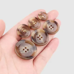 Selection of premium brown marbled resin buttons for coats shown on a palm