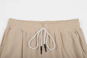 Detail view of elastic waistband on khaki corduroy pants with white drawstring