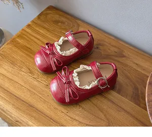 Vintage red Mary Jane shoes for girls with lace trim and bow detail on wooden background