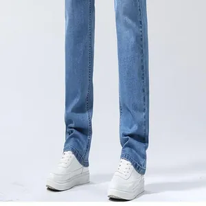 Detail of men's loose straight leg blue denim jeans with white platform sneakers.