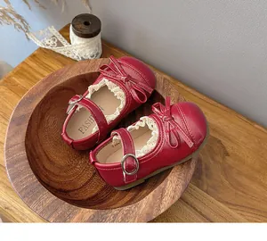Close-up of red Mary Jane shoes with bow and lace detail