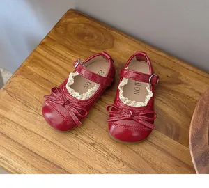 Macro view of red girls Mary Jane shoes featuring delicate lace trim and a sweet bow