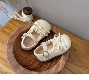 Close-up view of beige baby Mary Jane shoes with delicate lace and bow detail