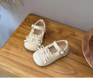 Close-up of girl's cream Mary Jane shoes with delicate lace and bow details