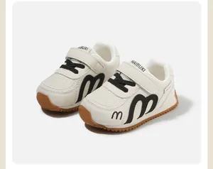 Detailed macro view of children's white sports shoes featuring black m logo and gum sole