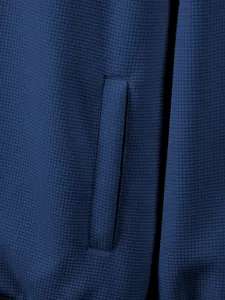 Close-up detail of navy blue waffle knit jacket showing pocket texture and fine stitching.