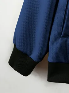 Detailed macro shot of blue waffle knit men's jacket showing black ribbed cuffs