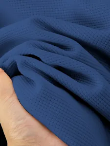 Detailed macro shot of deep blue waffle knit fabric texture for men's winter jacket.