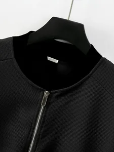 Close-up of black waffle knit texture and silver metal zipper on men's jacket