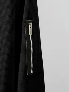 Macro view of men's waffle knit jacket featuring a black sleeve zipper pocket detail.