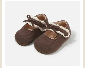 Detail view of brown toddler shoes with delicate lace trim and bow knot accents.